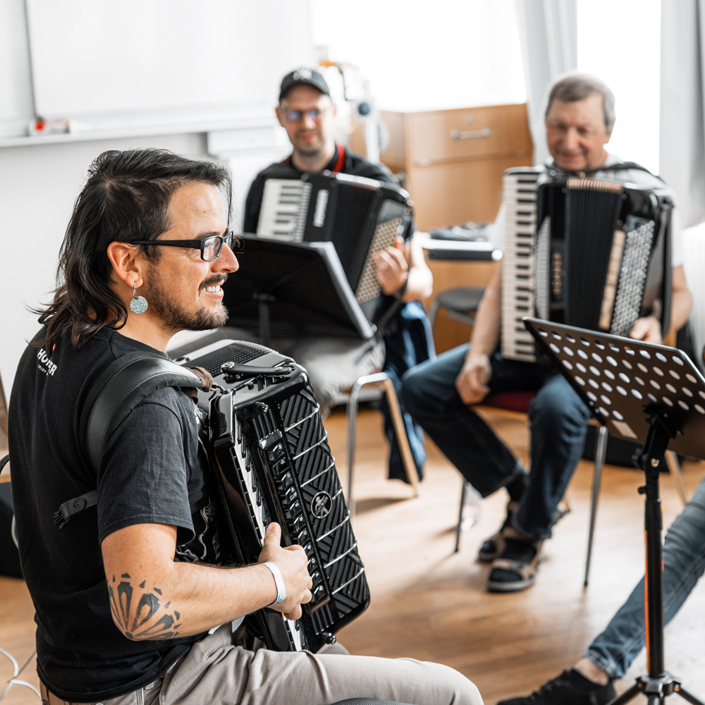 Dozent Alex Almedia der vor Akkordeon- Schülern etwas auf dem Akkordeon vorspielt