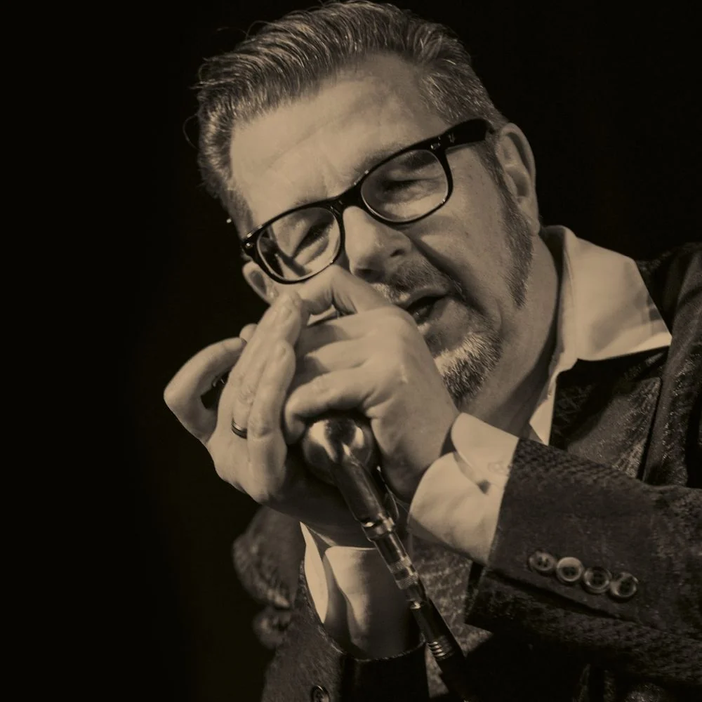 Dozent Dieter Kropp in schwarz weiß, er spielt mit der Mundharmonika in ein Mikrofon