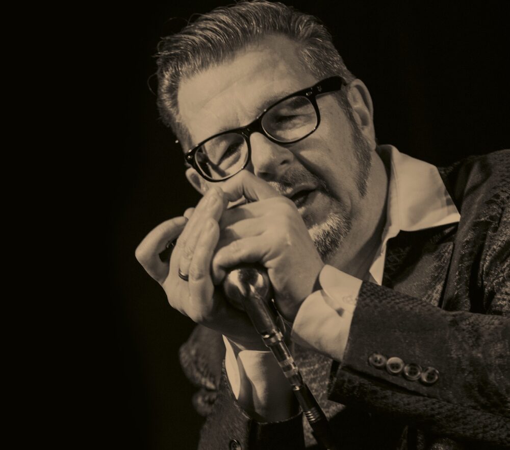 Dozent Dieter Kropp in schwarz weiß, er singt in ein Mikrofon