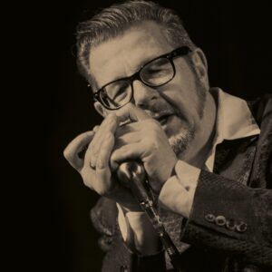 Dozent Dieter Kropp in schwarz weiß, er singt in ein Mikrofon