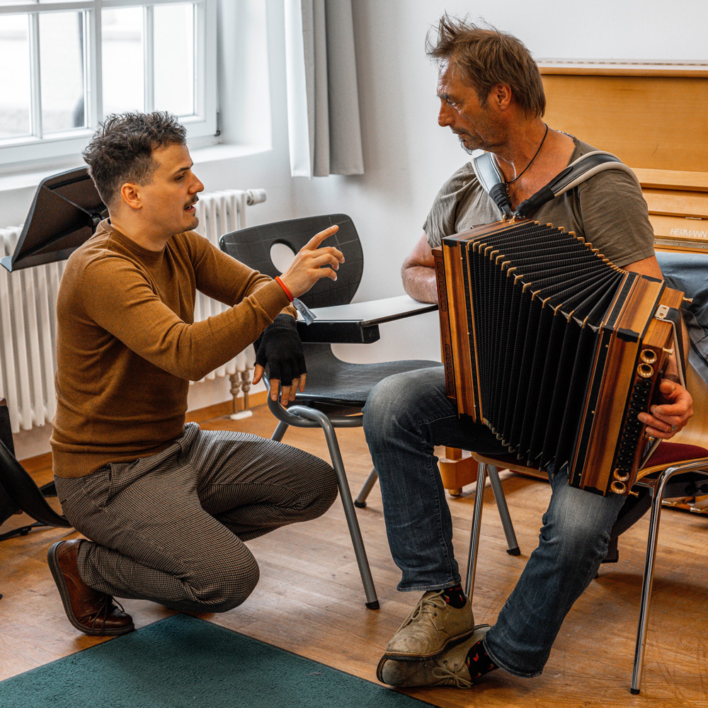 Dozent Jakob Steinkellner der sich beim Akkordeon spielen mir einem Schüler unterhält