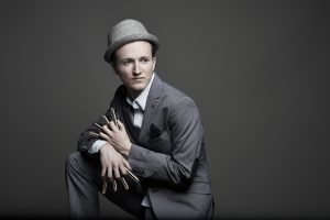 Musiker Konstantin Reinfeld trägt einen grauen Anzug und einen hellgrauen Hut