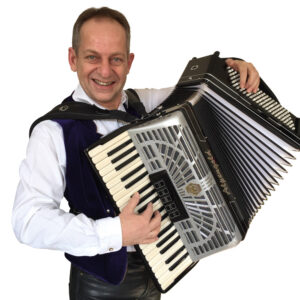 Dozent Turbo- Reini der Akkordeon spielt und in die Kamera lächelt