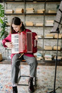 Jugendliche die auf einem roten Akkordeon übt