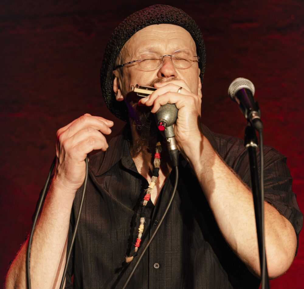 Musiker Joe Filisisko auf der Bühne der eine Mundharmonika spielt