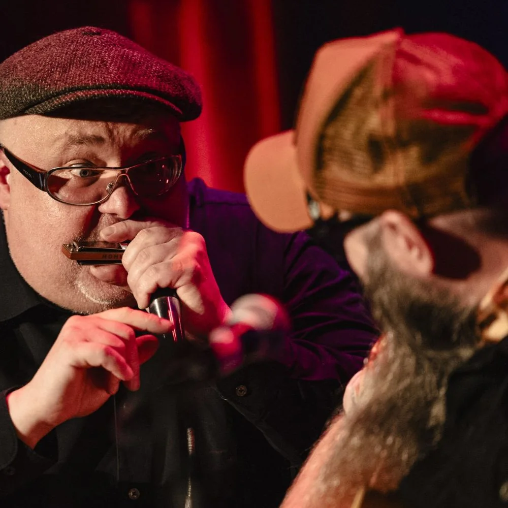 Zwei Musiker auf der Bühne performen auf der Mundharmonika und der Gitarre