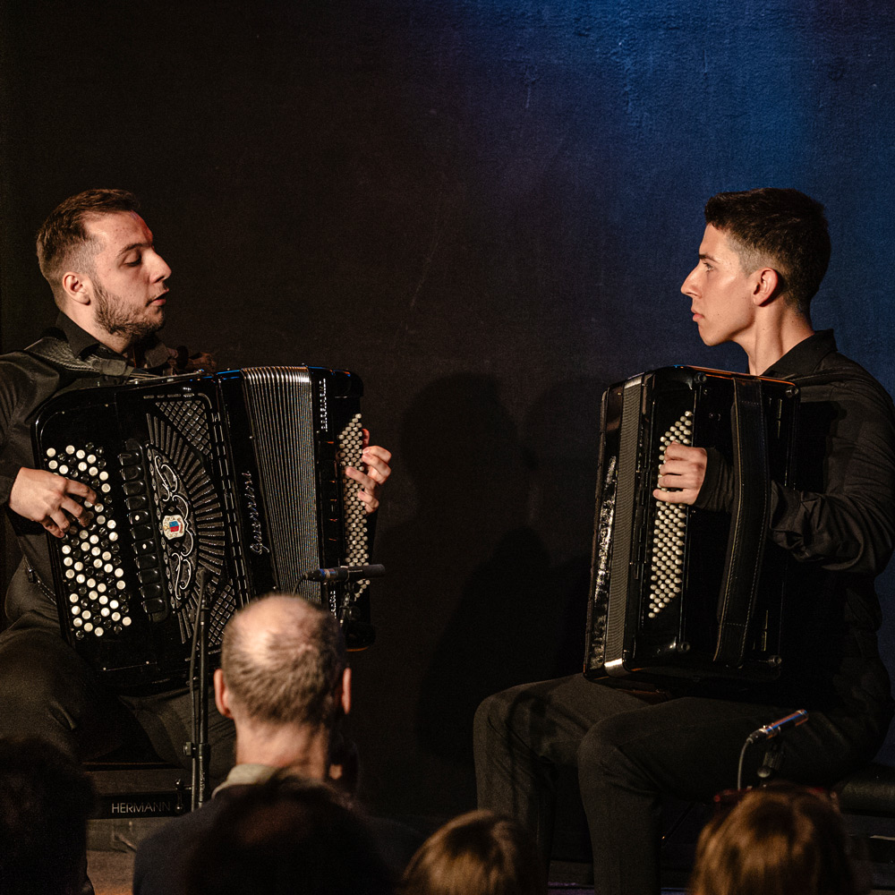 Zwei Akkordeon Spieler sie sich auf der Bühne beim senior- final Konzert gegenüber sitzen vor Publikum