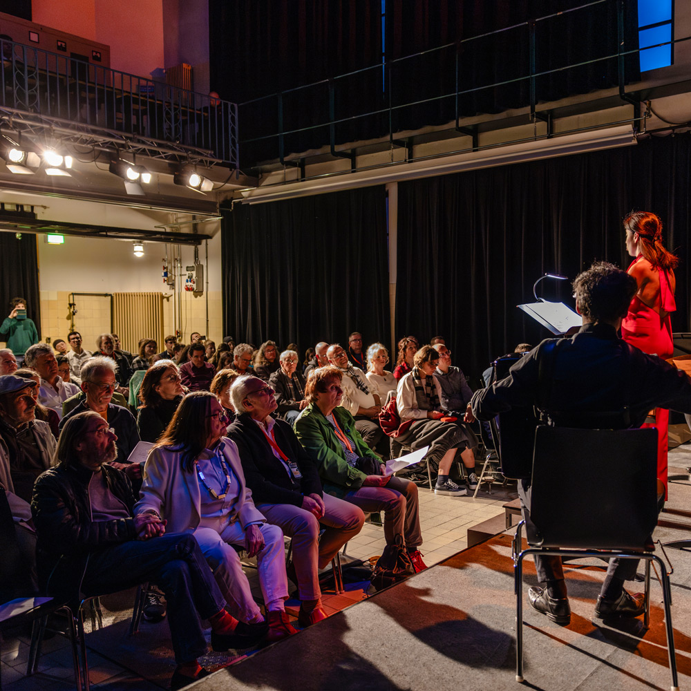 Vollbesetzter Konzertsaal imHohnerkonservatorium und zei Musizierende auf der Bühne