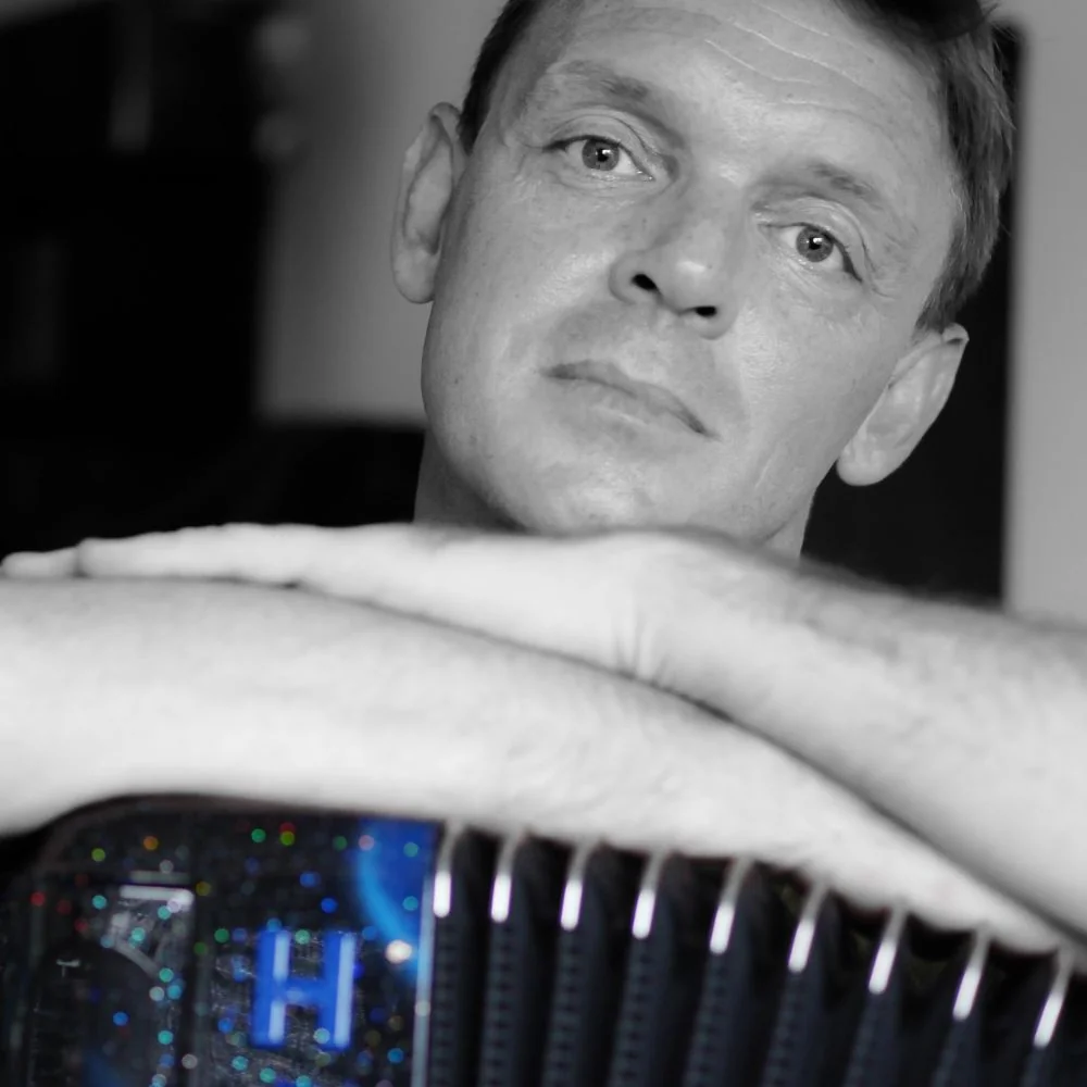 Dozent Frederic Deschamps lehnt auf einem Akkordeon, das Bild ist schwarz-weiß gehalten